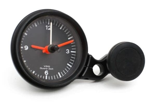 A black clock with red hands and a button.